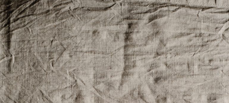 A texture of wrinkled grey fabric.