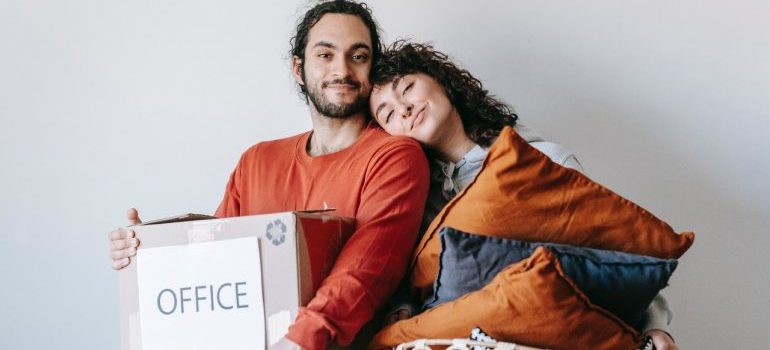 a couple holding a box and pillows 