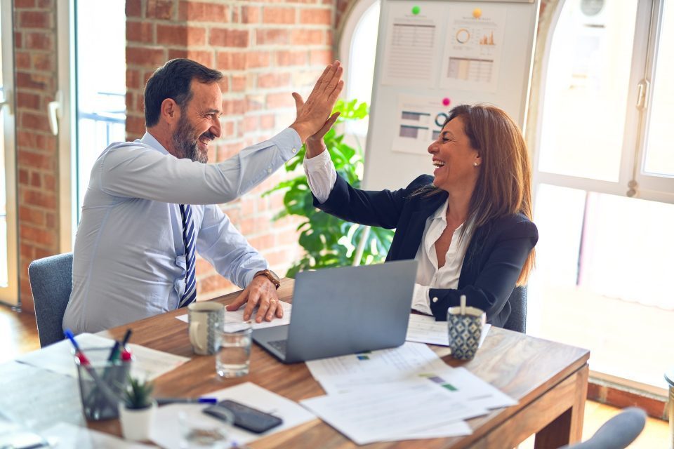 two middle aged colleagues giving each other high five