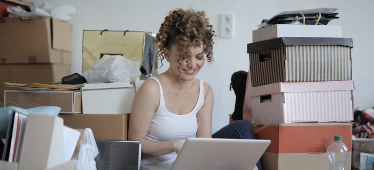 a girl using a laptop while surrounded by boxes