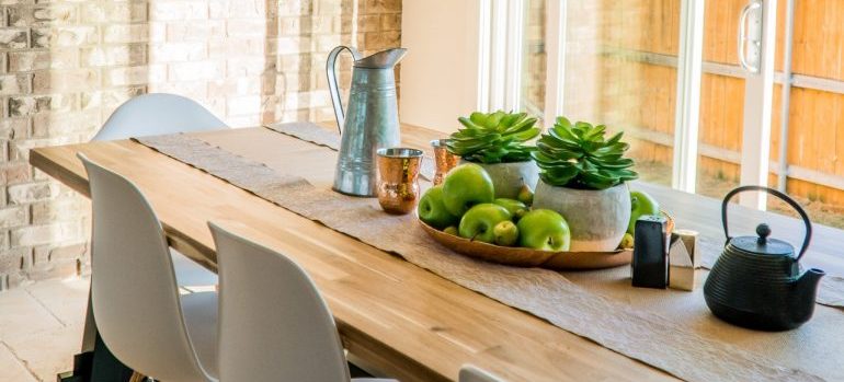 a jug, a few apples, two succulents and a kettle on a wooden table
