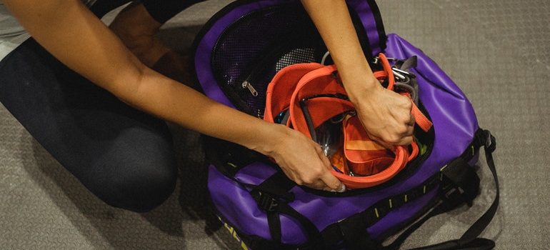 Unrecognizable woman packing climbing gear into a purple bag.