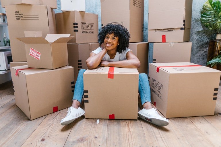 A women sitting on a floor with a box around her and one in front of her, think about Mistakes to Avoid When Moving to Sterling