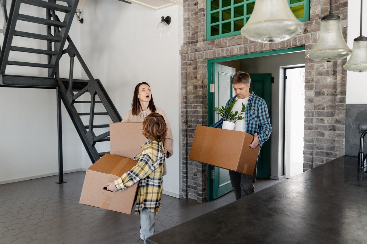 a family of three walking into their new home while carrying boxes