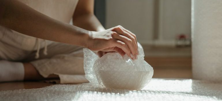 Woman wrapping fragile items with bubble wrap