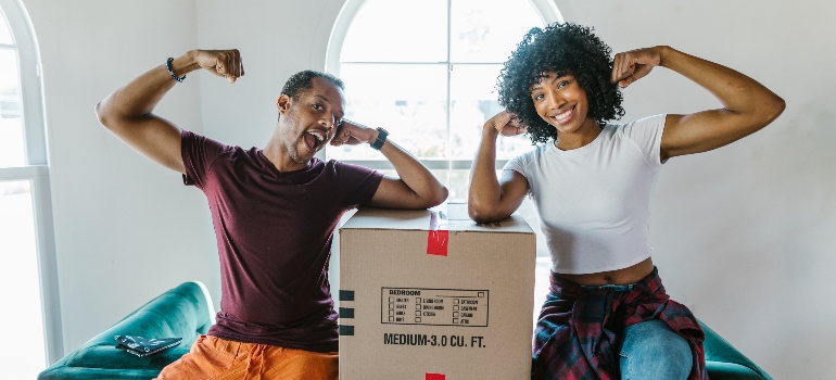 mover and a girl with a box between them smiling 