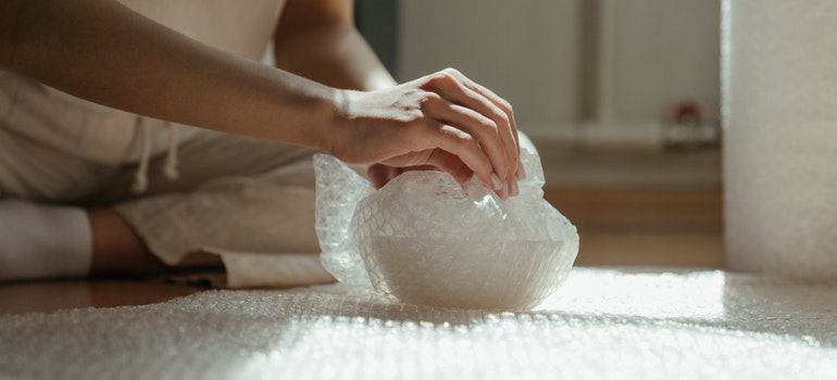 A person is wrapping a cup in bubble wrap.