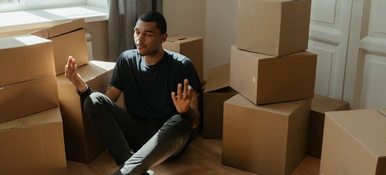 Man meditating among boxes