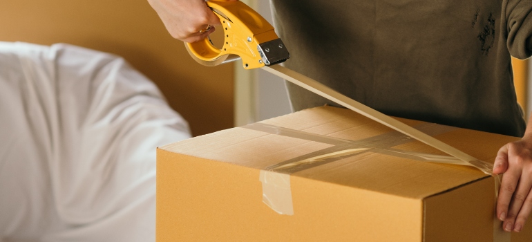 Person packing a box to simplify the difficulties of displacement by using Zippy Shell storage 
