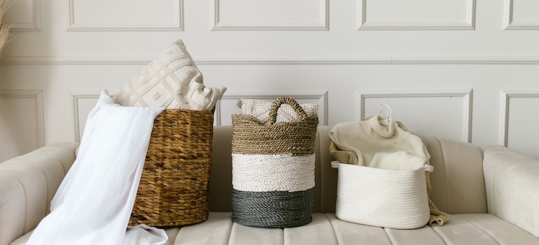 Clothes inside woven baskets on a bed represent items to store when preparing for long-term travel.