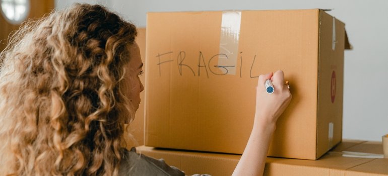 a woman labeling a box as fragile 