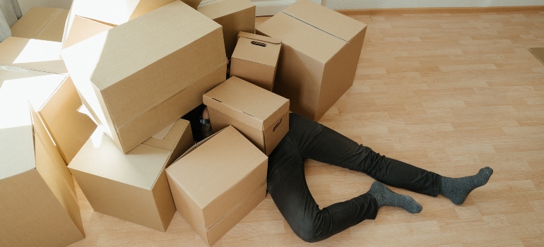 A man on the floor surrounded by moving boxes
