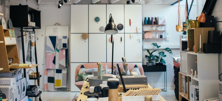 A modern and stylish interior of a shop with a line of home organization products on display, from shelves to desks, amidst a backdrop of colorful houseplants.